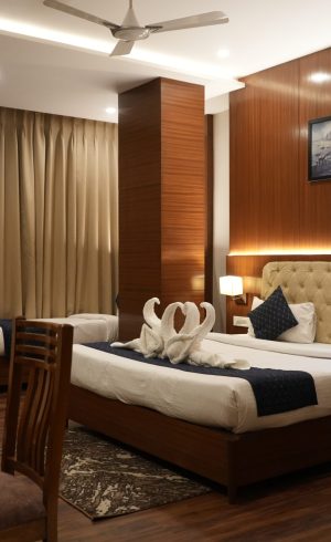 Warm, upscale hotel bedroom with king bed, towel swans, wood paneling, soft lighting, curtains, armchair, and ceiling fan; inviting mood.